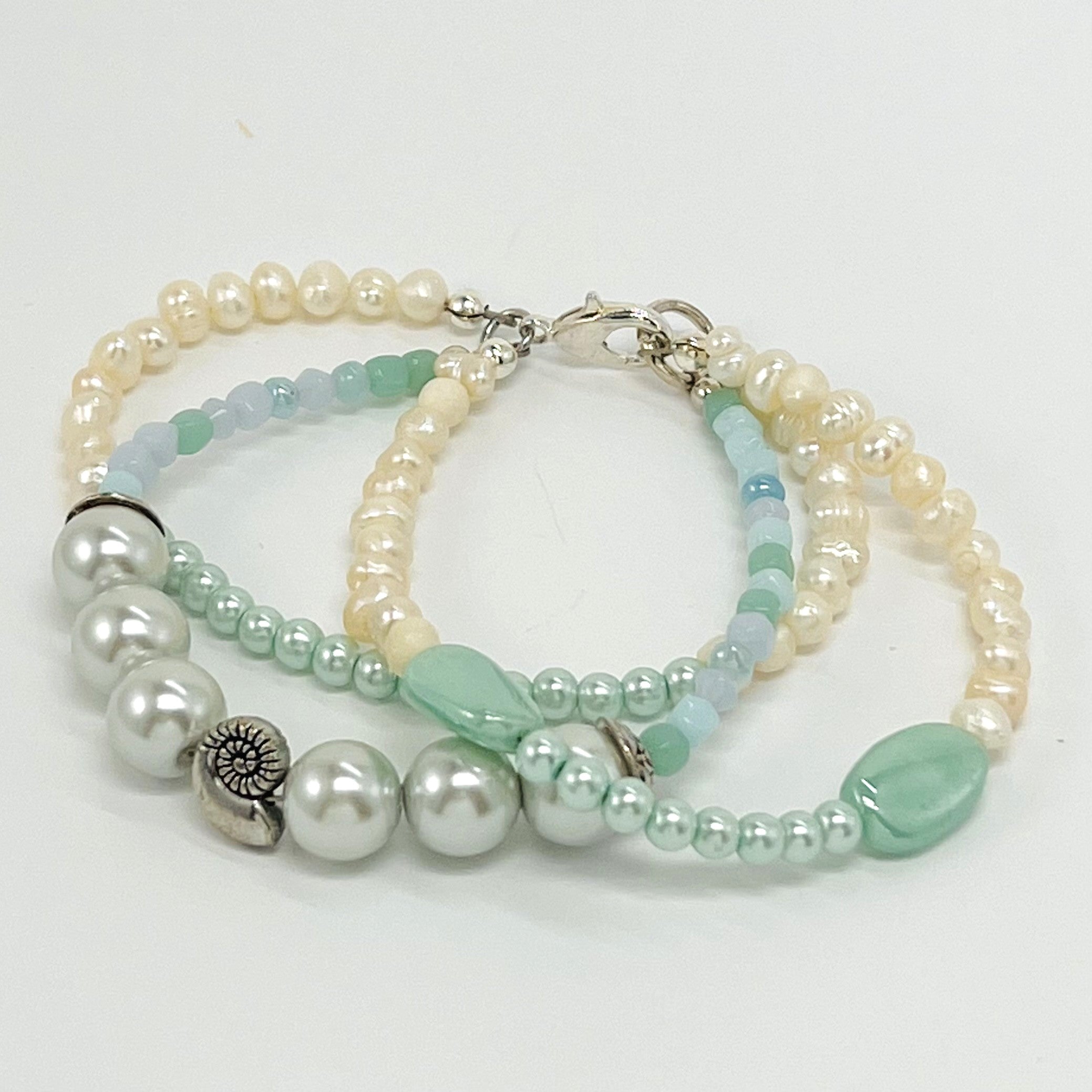 Fresh water pearls accompany minty green and palest blue glass beads on a triple strung bracelet and matching dangle earrings.