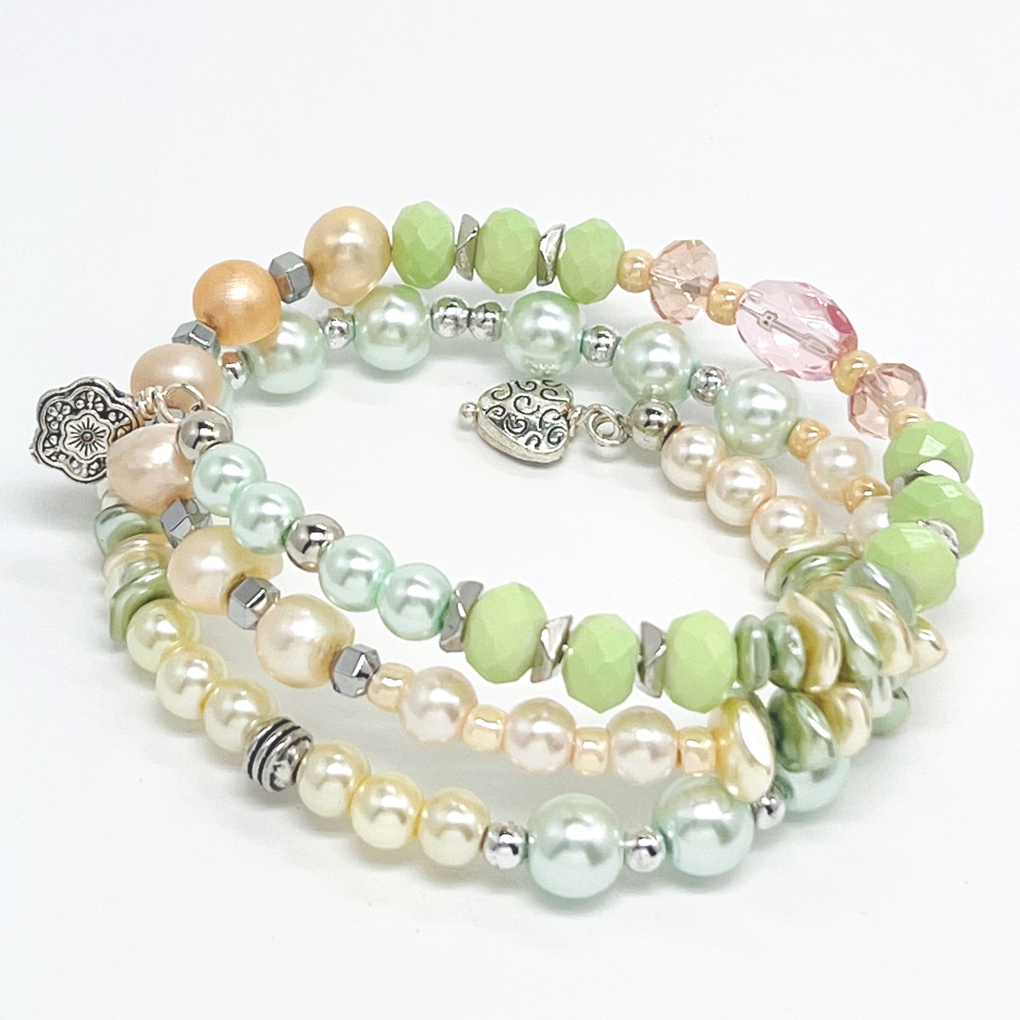 Playful pastels of green, peach, cream glass beads and fresh water pearls with silver plated accents and charms