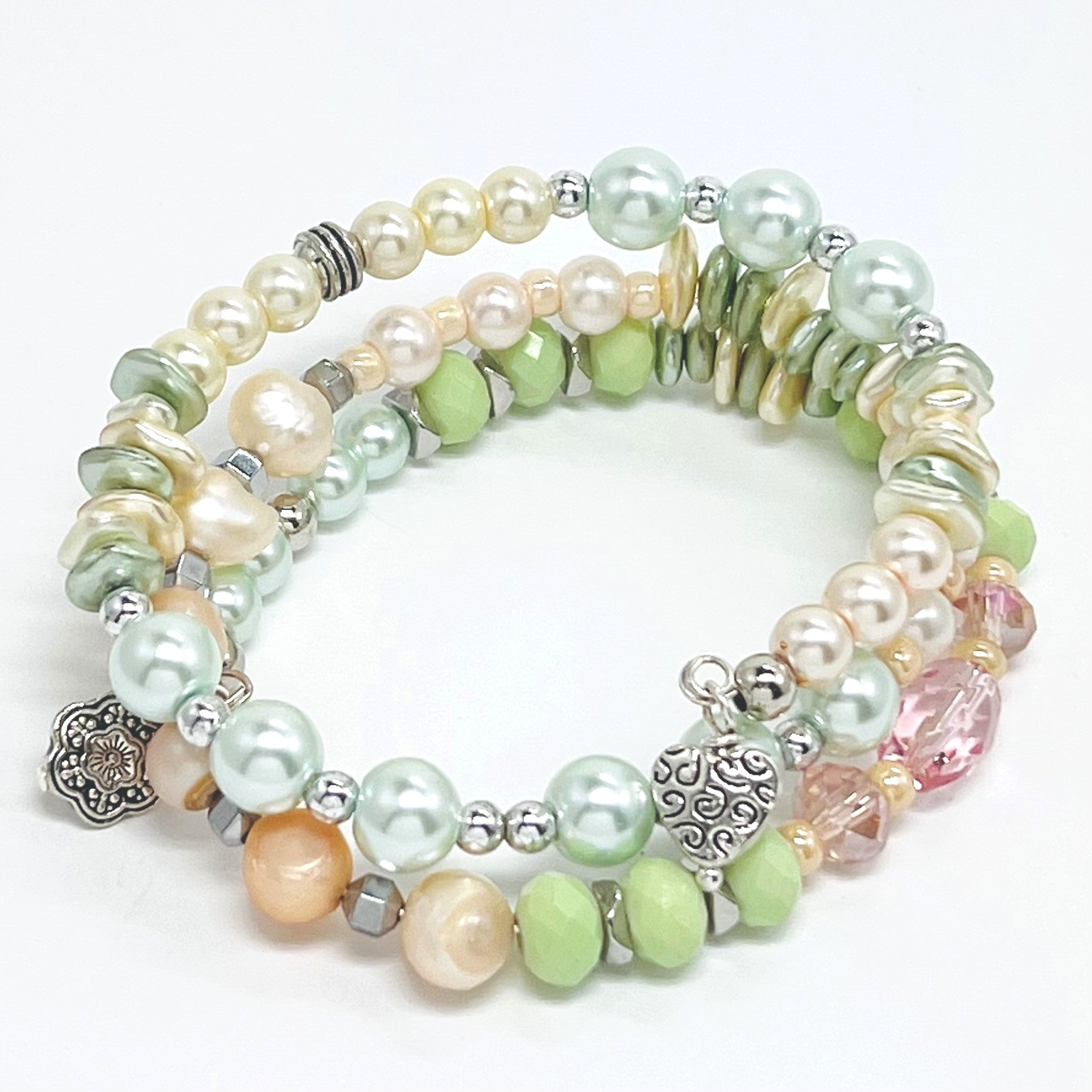 Playful pastels of green, peach, cream glass beads and fresh water pearls with silver plated accents and charms