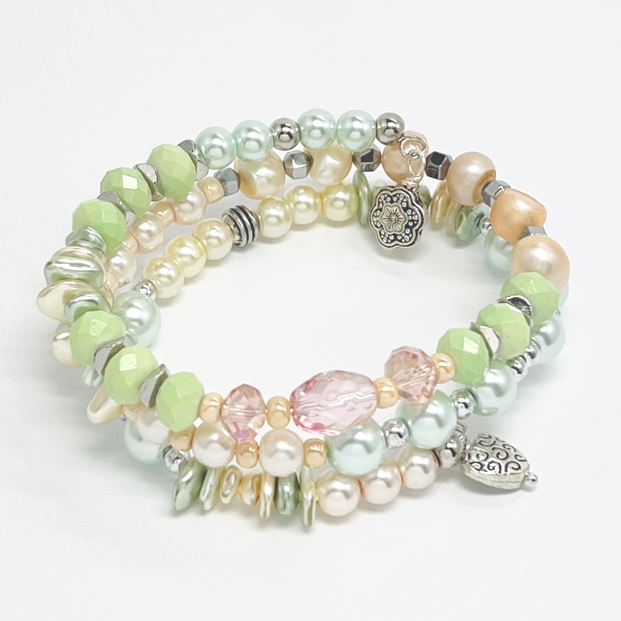 Playful pastels of green, peach, cream glass beads and fresh water pearls with silver plated accents and charms