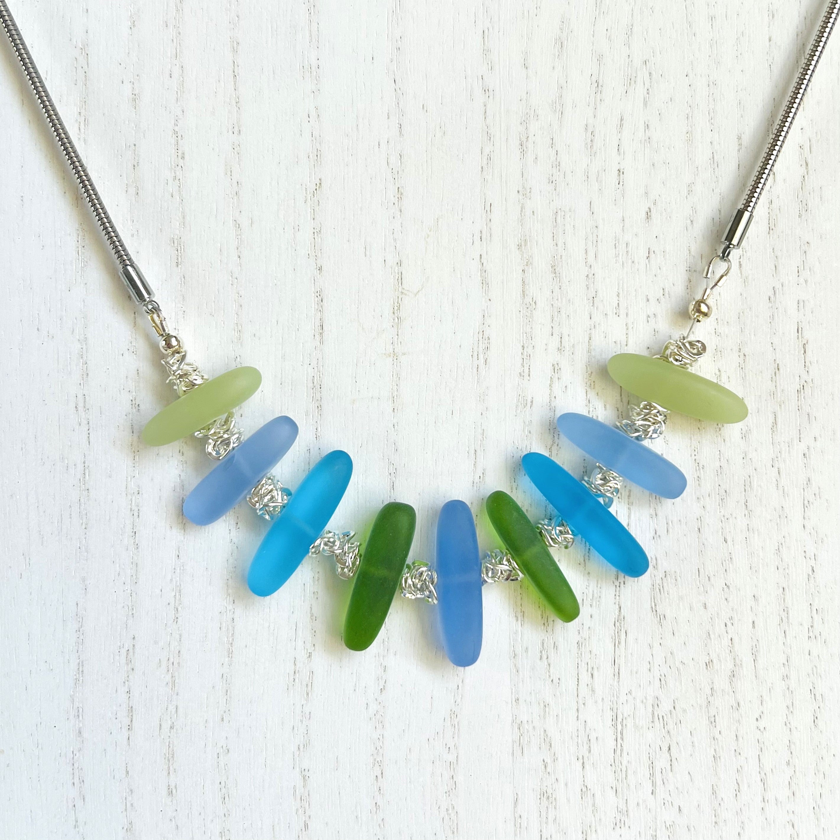 Cool Caribbean sea colors in frosty blue and green sea glass beads hanging on a silver plated snake chain with matching earrings