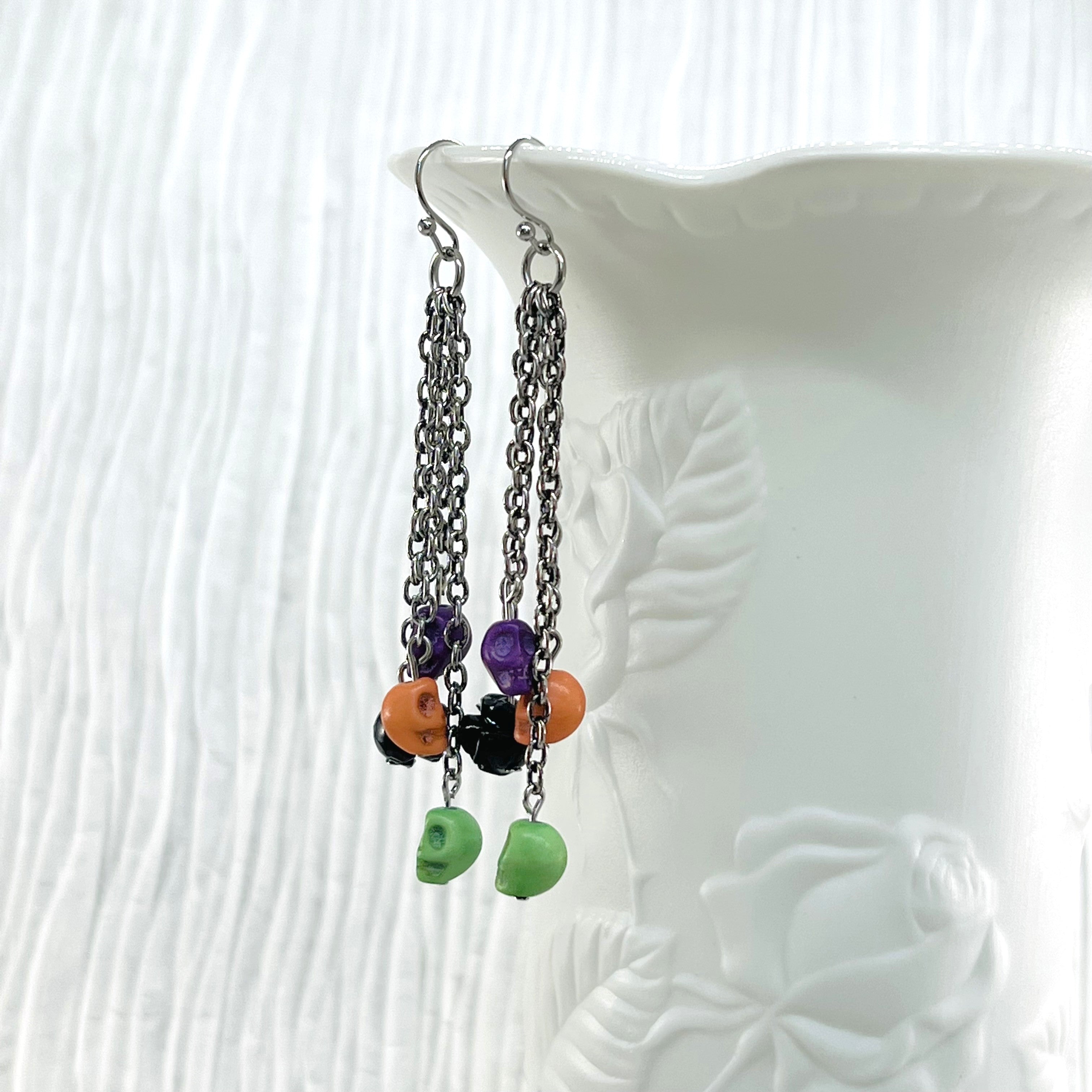 Halloween fun earrings green, orange, purple skulls and a black resin flower, silver ear wires