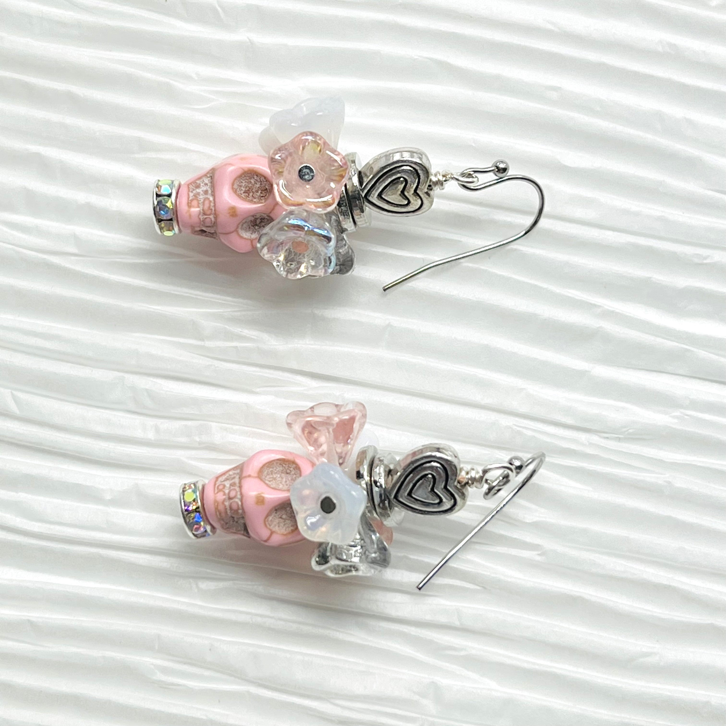 Fancy pink Wagnerite skull earrings topped with a row of lovely pink, white and silver resin flowers