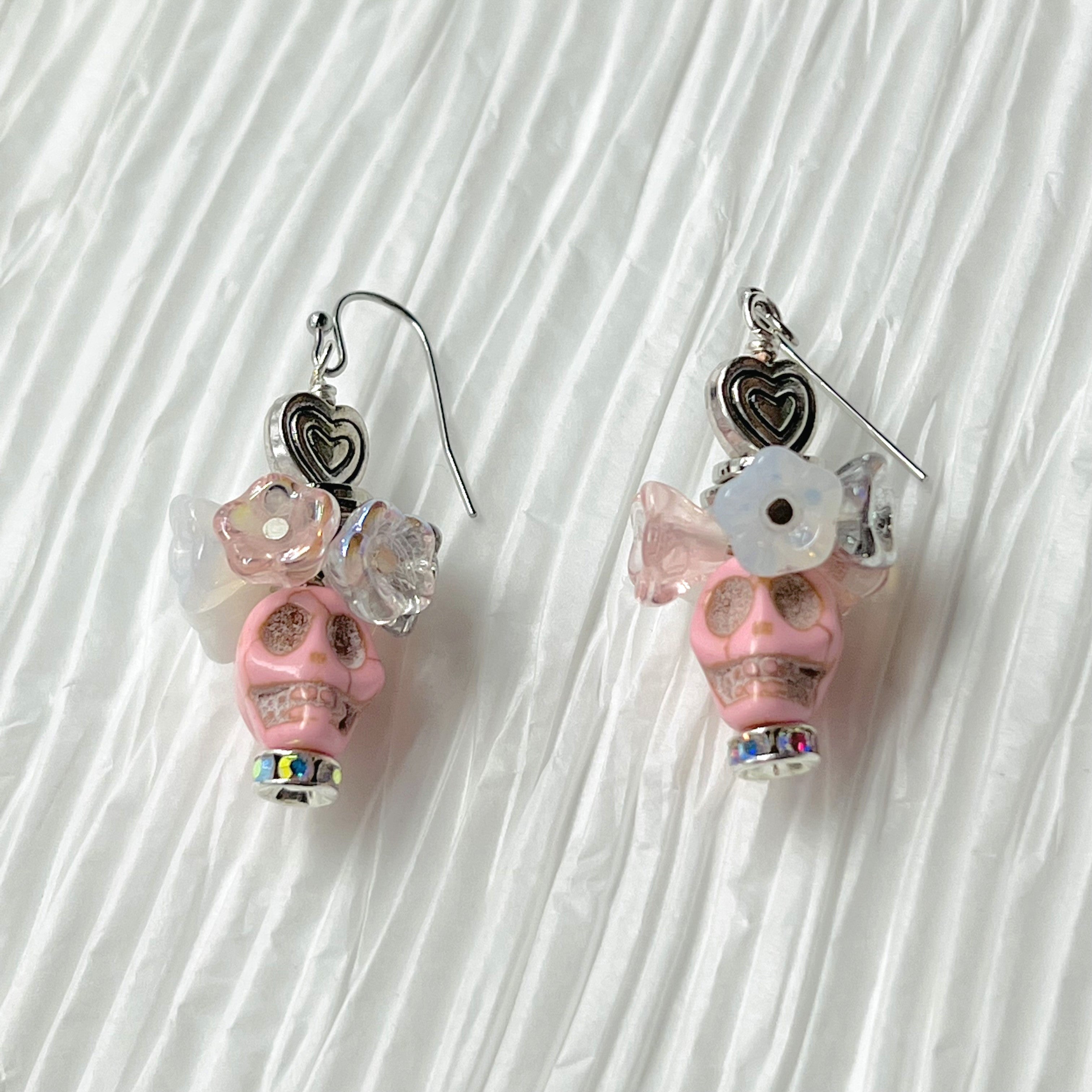 Fancy pink Wagnerite skull earrings topped with a row of lovely pink, white and silver resin flowers