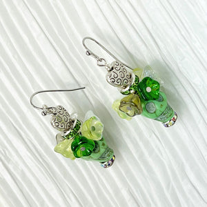 Pretty green Wagnerite skull earrings topped with a row of resin flowers in white, green and silver