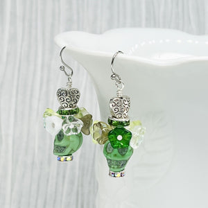 Pretty green Wagnerite skull earrings topped with a row of resin flowers in white, green and silver