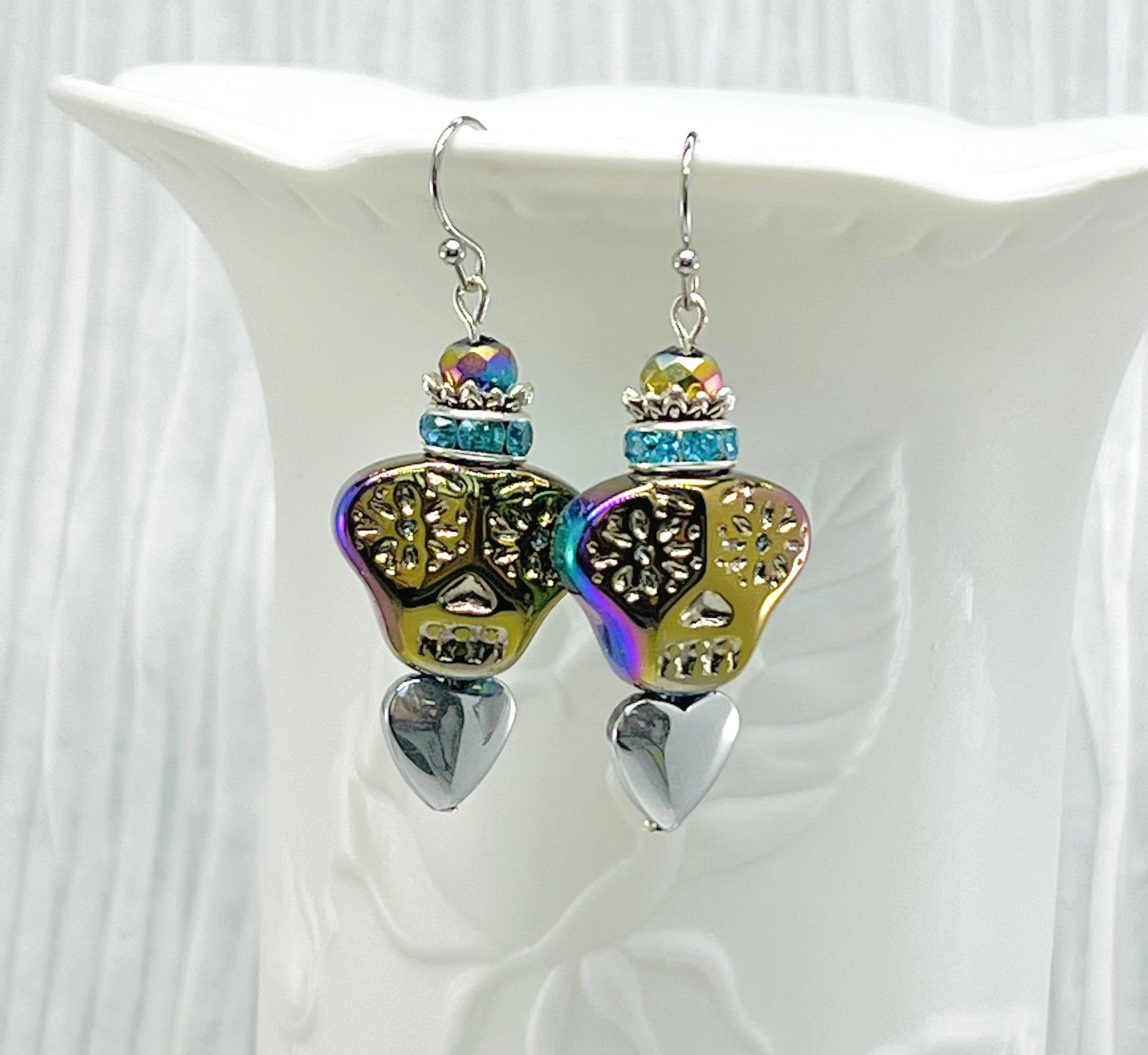 Colorful iridescent glass skulls top a silver heart and are crowned by a sparkling turquoise rhinestone rondel