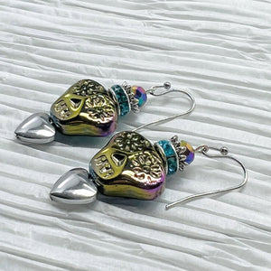 Colorful iridescent glass skulls top a silver heart and are crowned by a sparkling turquoise rhinestone rondel