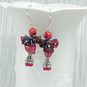 Passionate red Wagnerite skull earrings topped with a row of colorful resin flowers in red, blue and purple