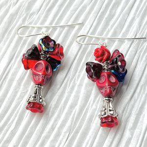 Passionate red Wagnerite skull earrings topped with a row of colorful resin flowers in red, blue and purple