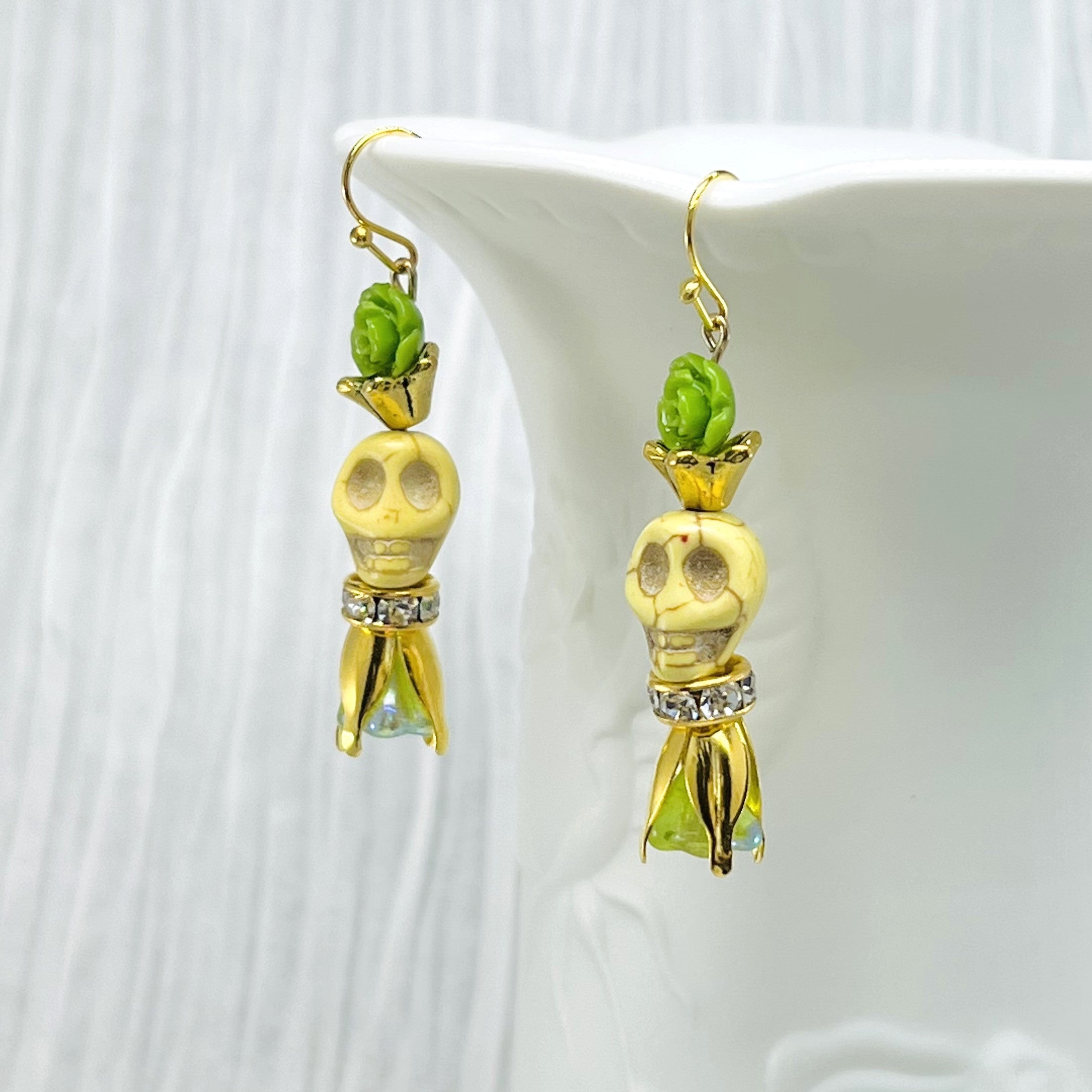 Lovely pale yellow Wagnerite skull earrings with green resin flowers accented in gold