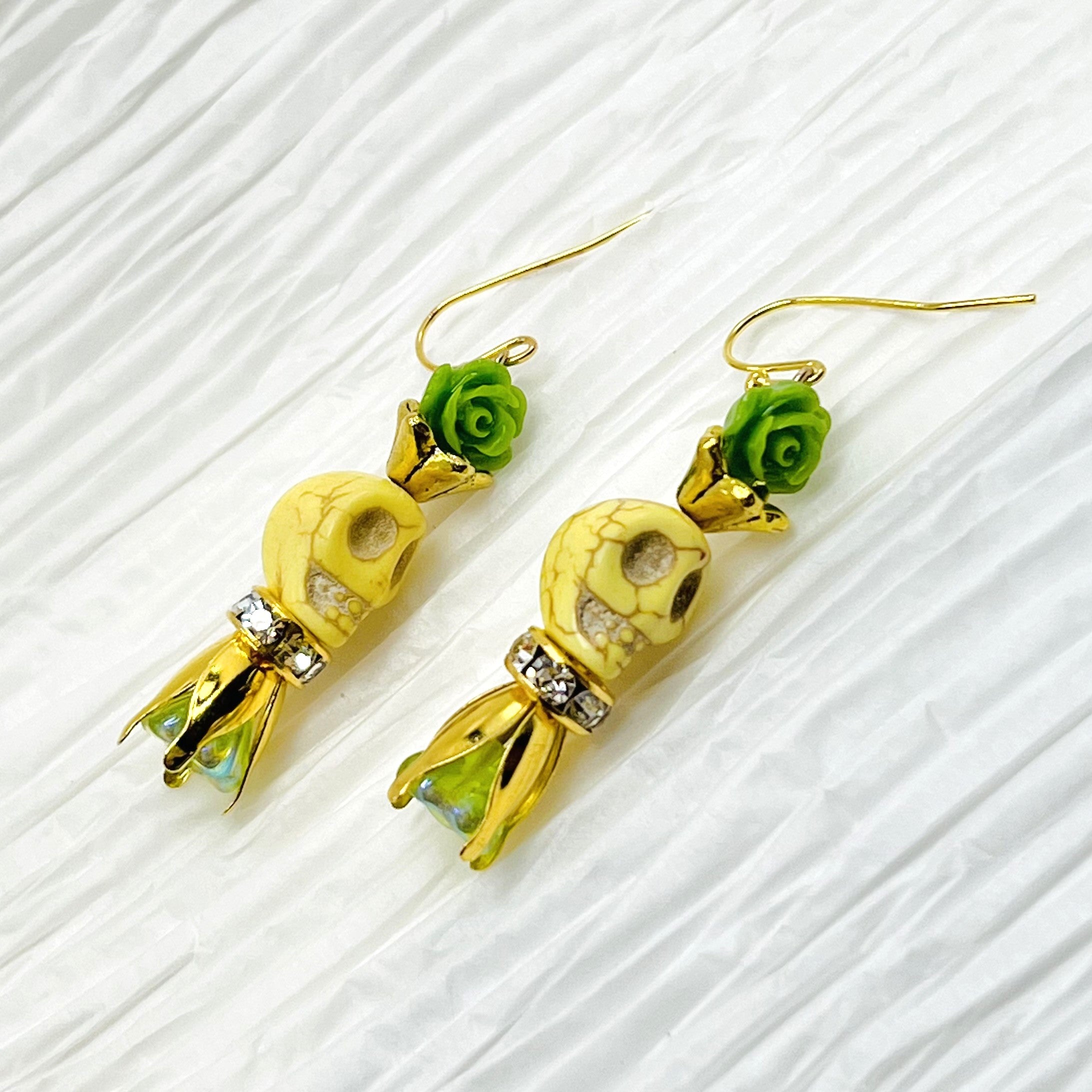 Lovely pale yellow Wagnerite skull earrings with green resin flowers accented in gold