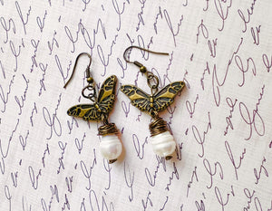 Earrings with a large fresh water pearl and a butterfly that dangle from an antique brass ear wire.