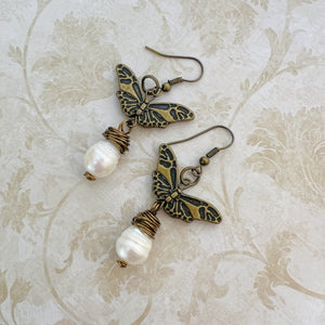 Earrings with a large fresh water pearl and a butterfly that dangle from an antique brass ear wire.